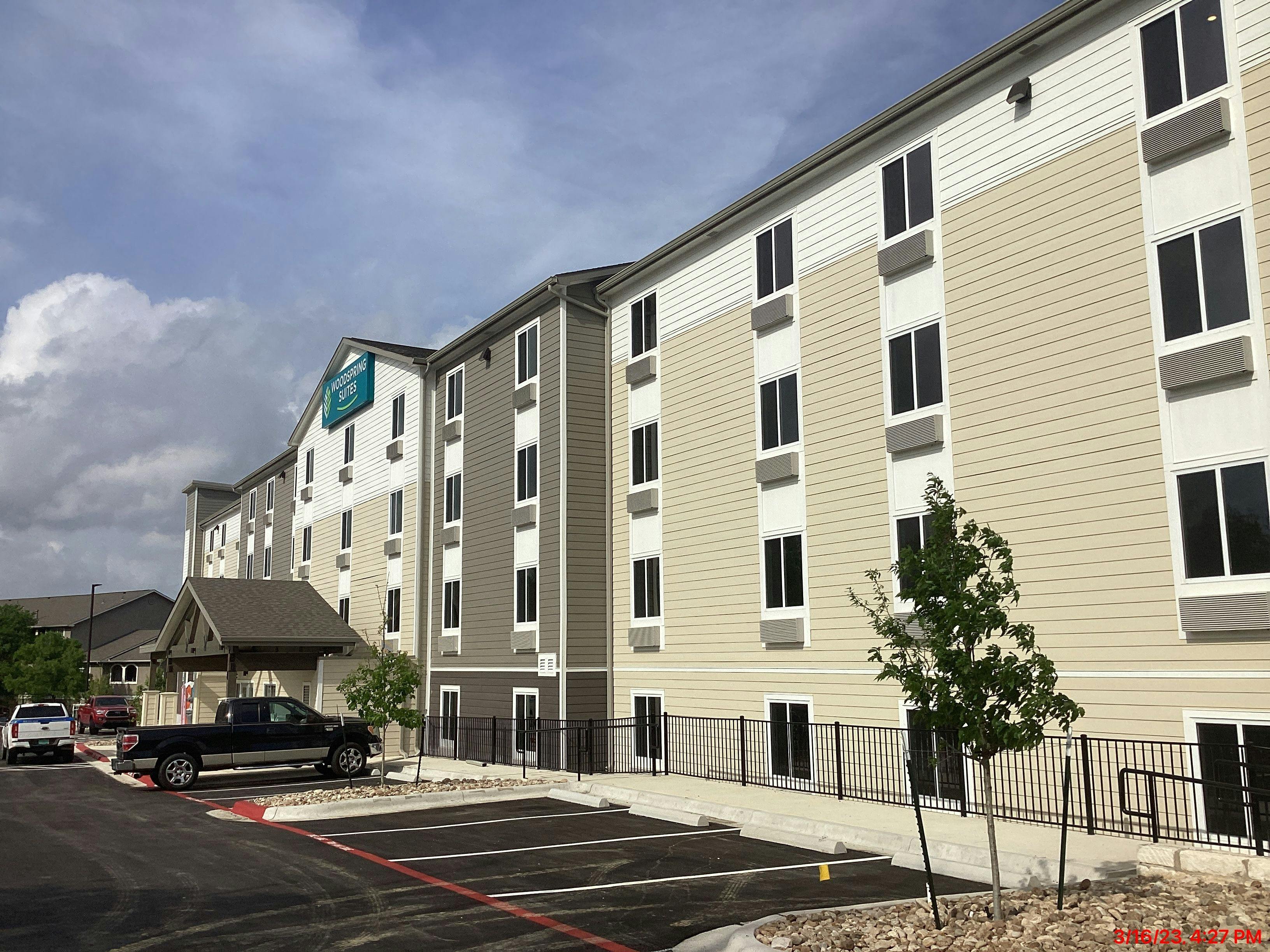 Exterior view of the front to the WoodSpring Suites hotel in Austin, TX.